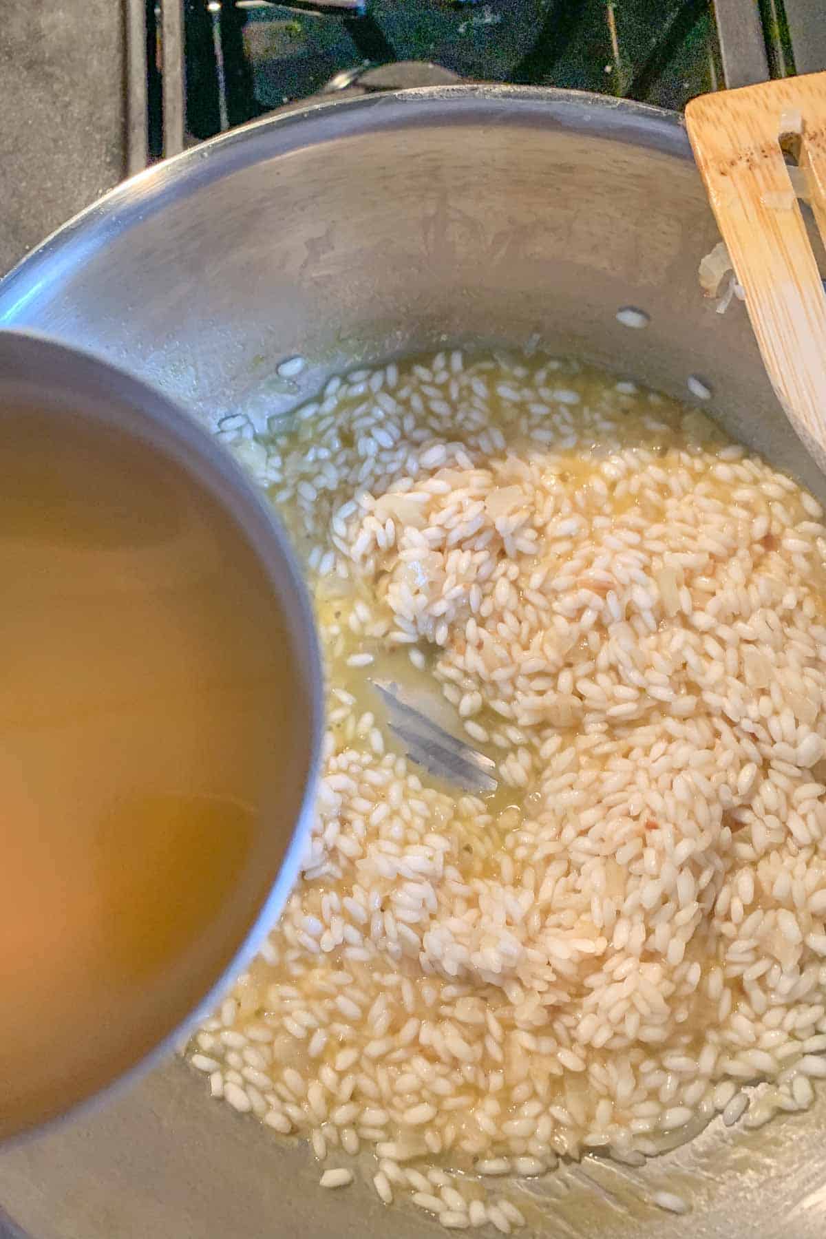 Pouring broth into a pan of risotto.