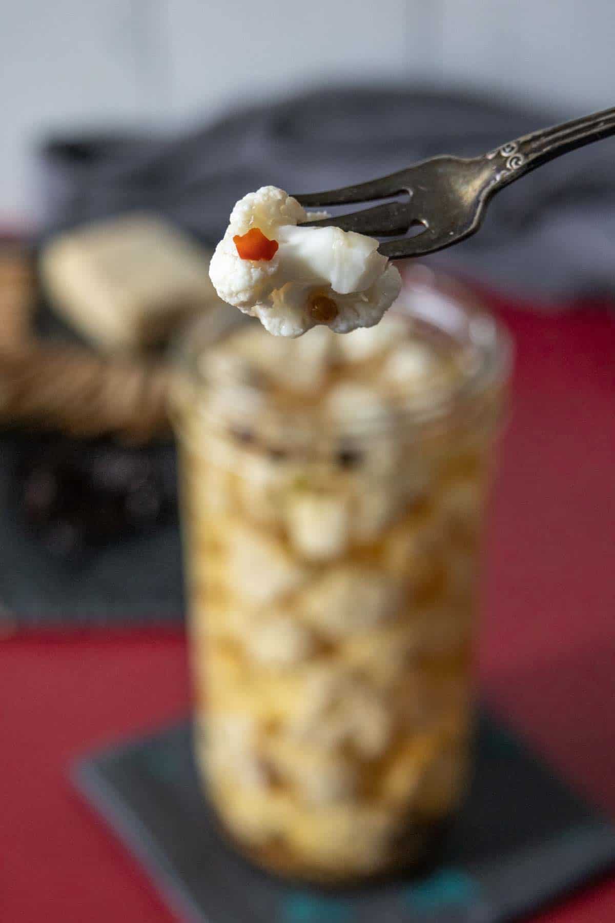 Pickle fork holding a piece of pickled cauliflower.