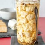 Pickled cauliflower in a jar on a cocktail napkin.