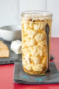 Pickled cauliflower in a jar on a cocktail napkin.