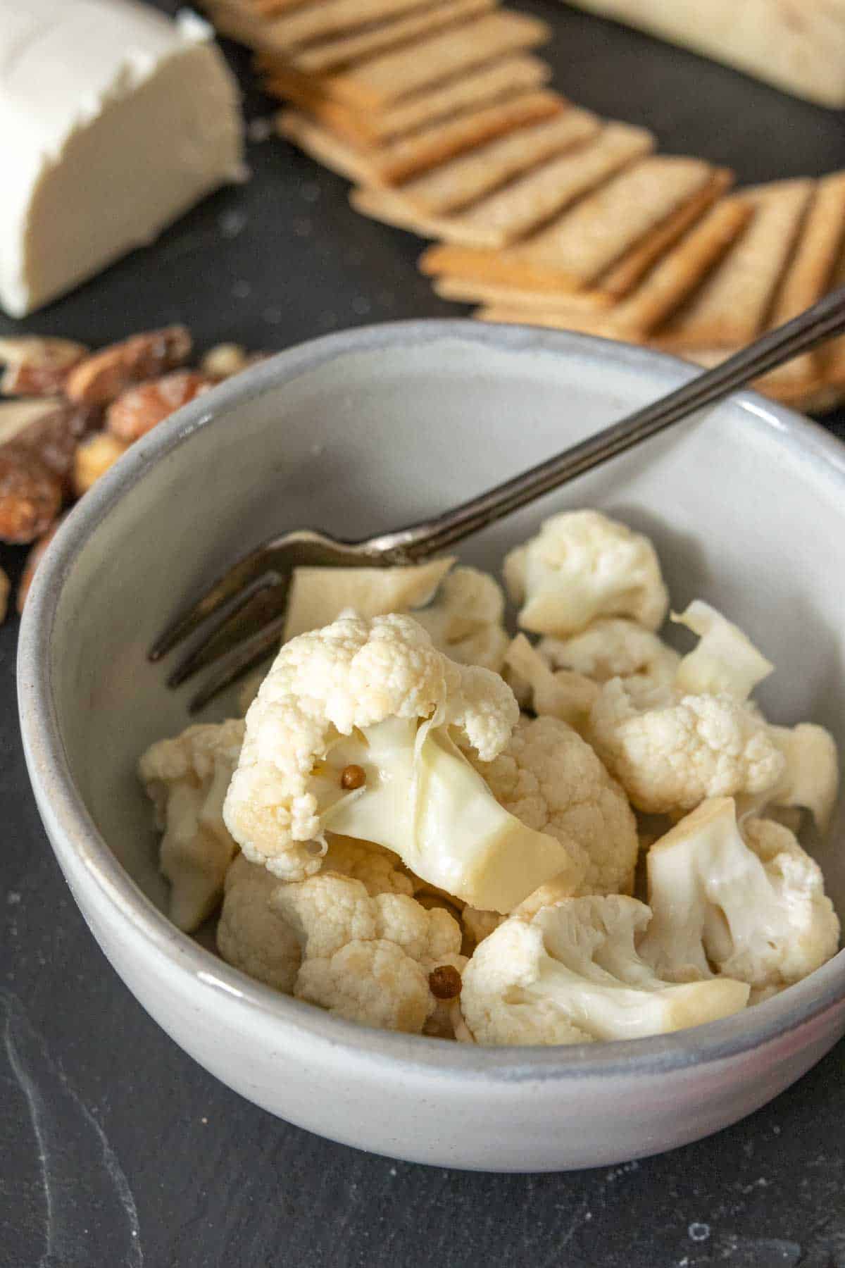 Bowl of pickled cauliflower on a cheese tray.