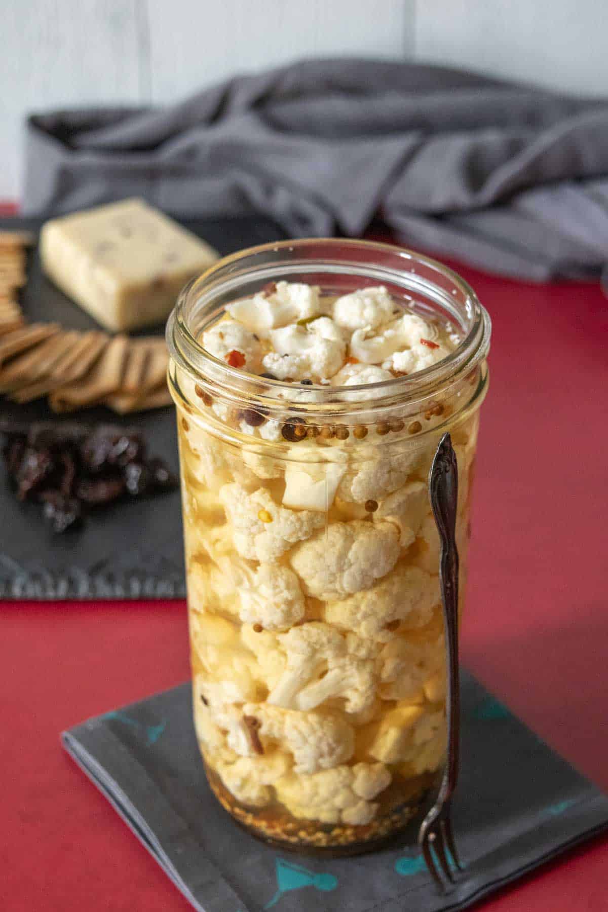 Jar of pickled cauliflower with a fork beside.