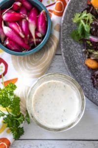 Overhead photo of ranch dressing in a jar with salad ingredients nearby.