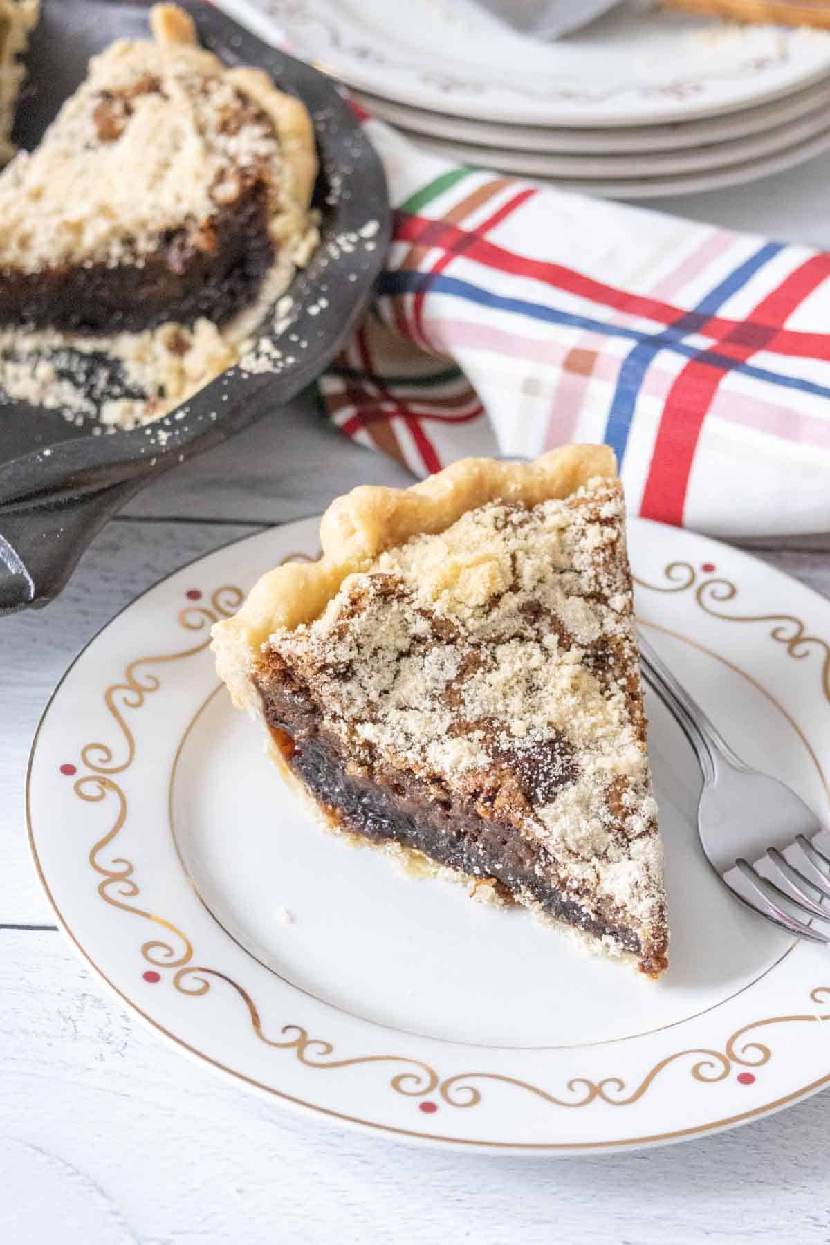 Slice of shoofly pie on a white plate with a fork beside.