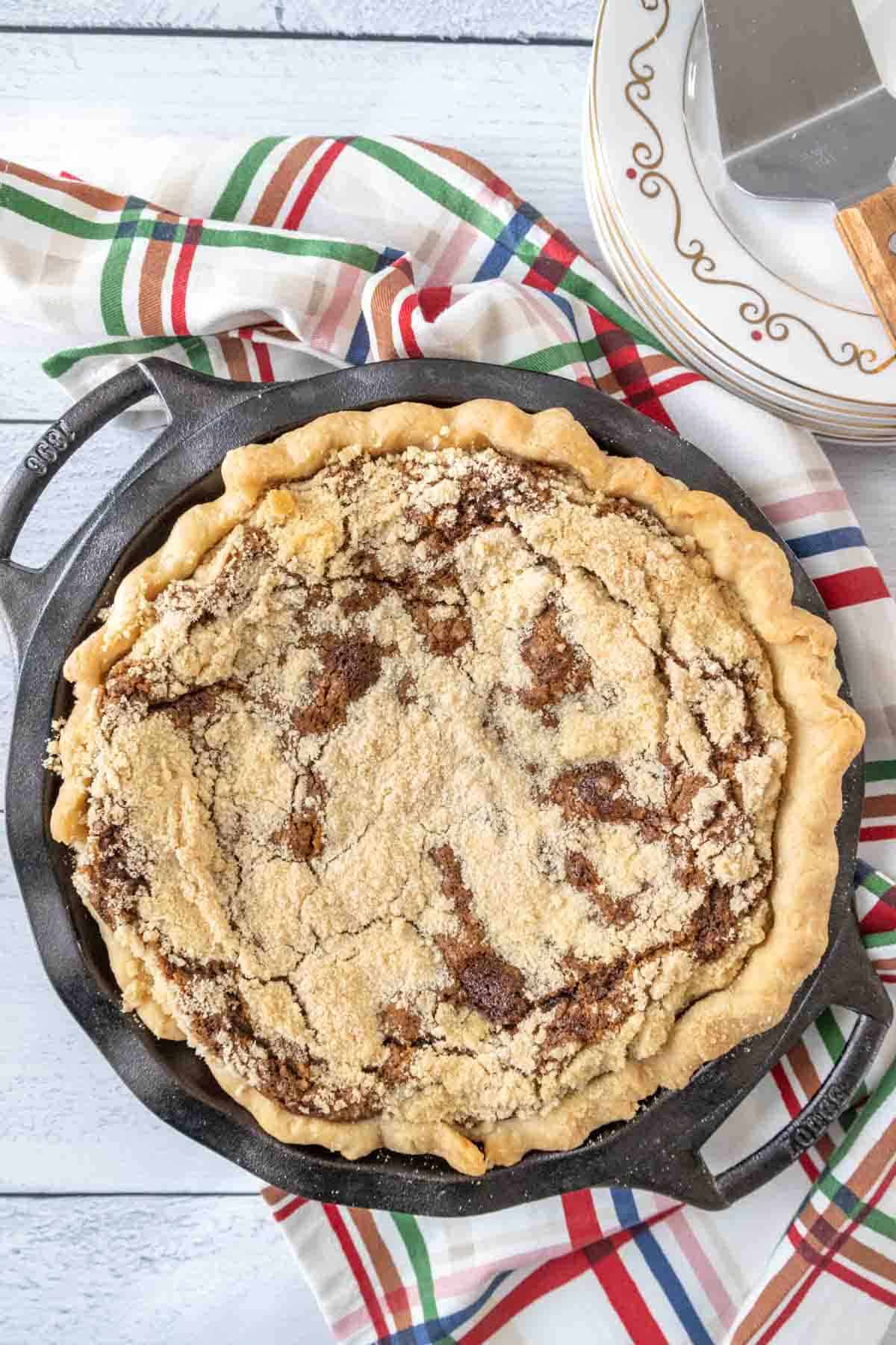 Whole shoofly pie in a pie pan shot from above with a colorful plaid napkin.