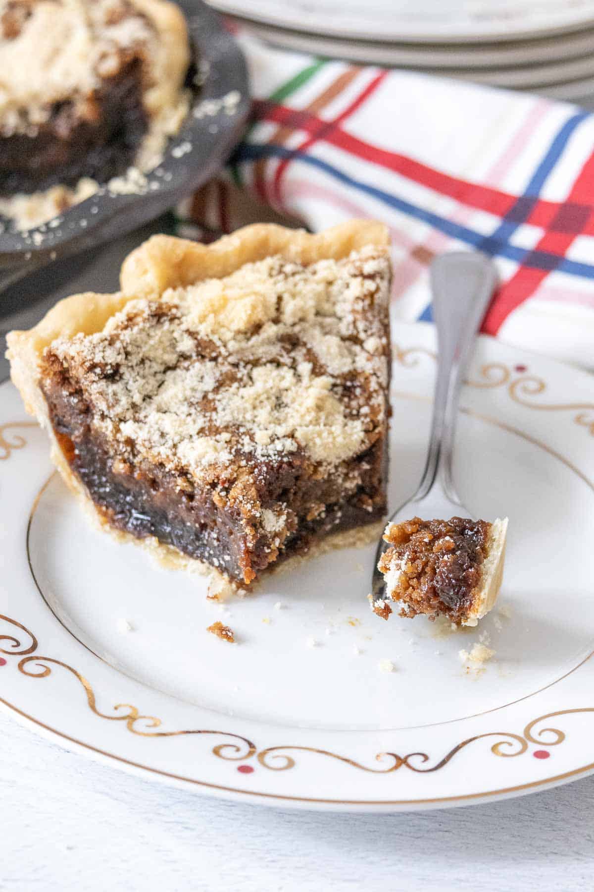 Slice of shoofly pie on a plate with a fork, a piece sitting on the fork.