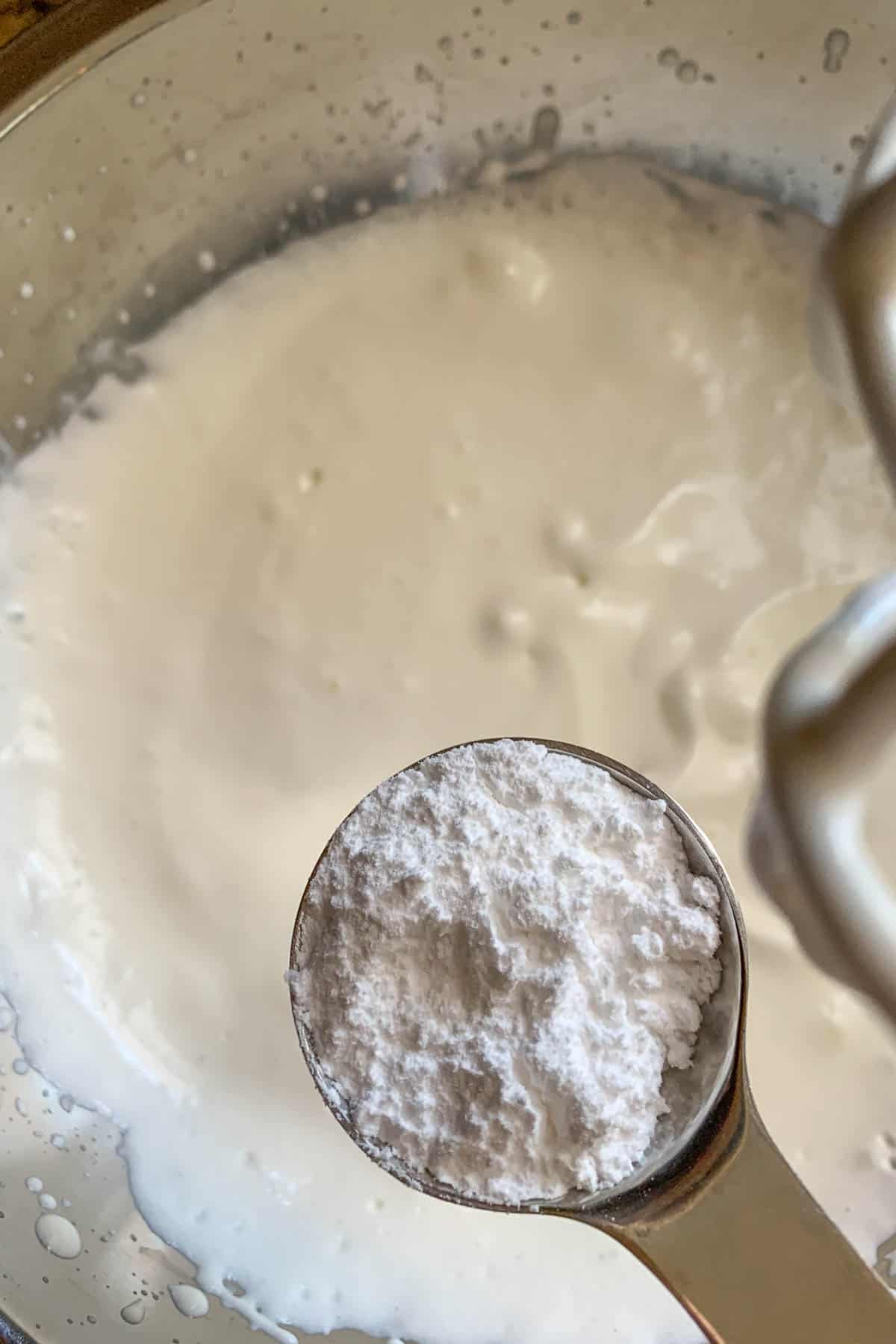 Powdered sugar being added to whipping cream.