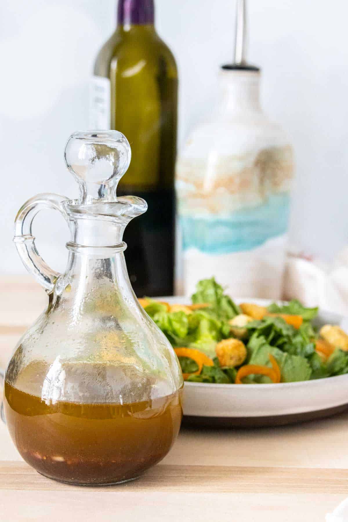Bottle of homemade balsamic vinaigrette in front of a salad.