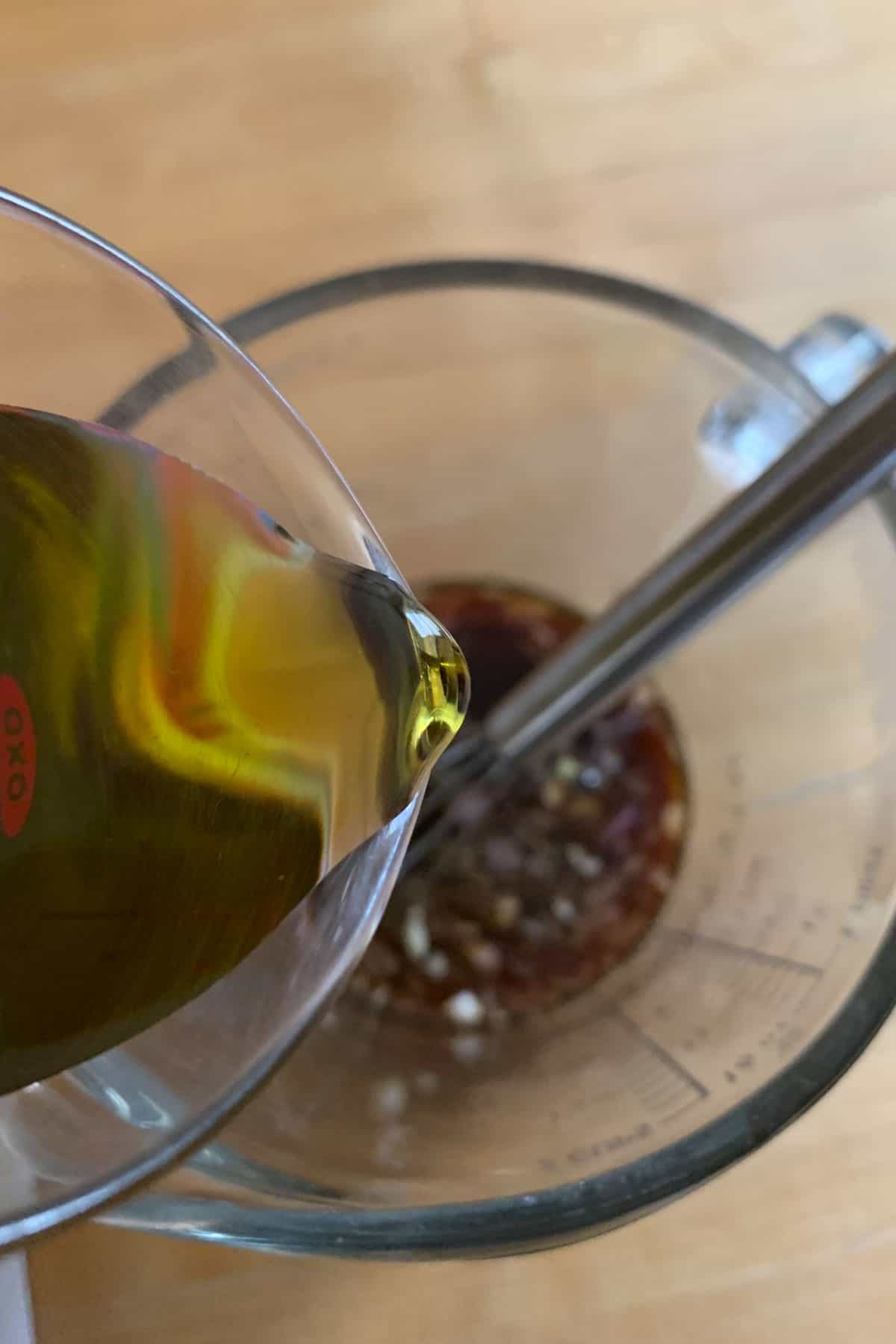 Pouring olive oil into balsamic vinaigrette.