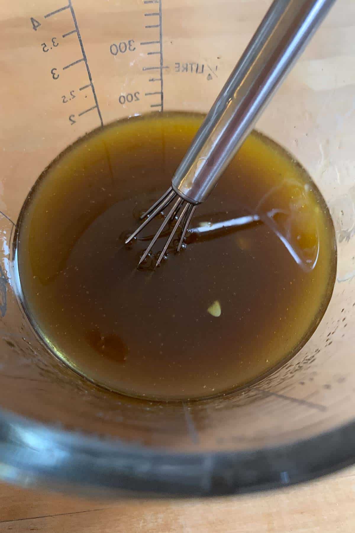 Whisking balsamic vinaigrette in a liquid measuring cup.