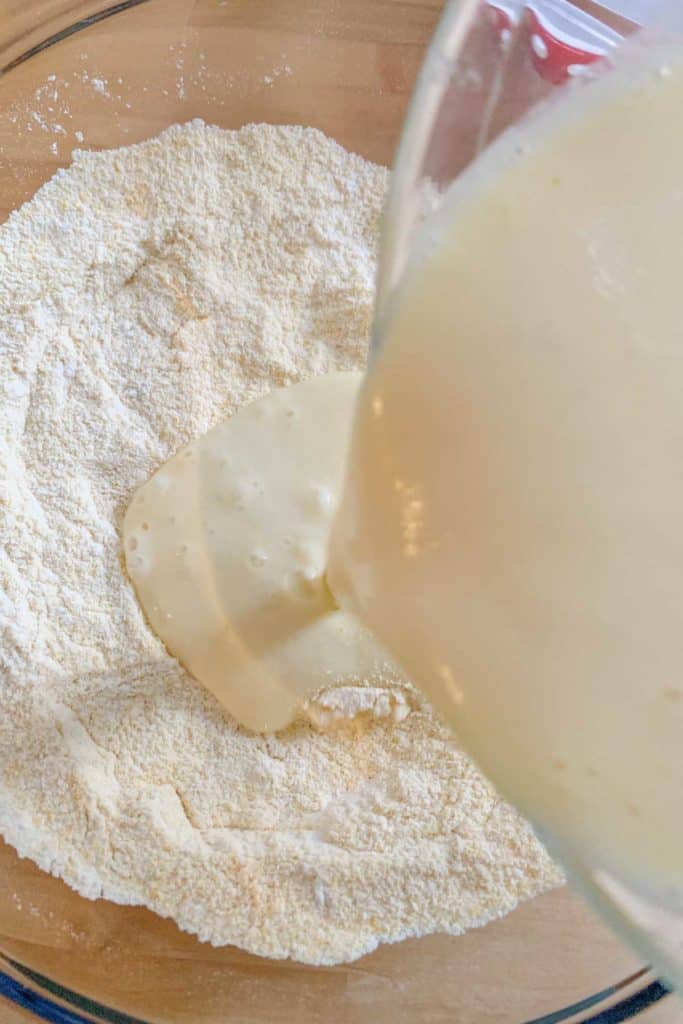 Pouring wet ingredients into dry ingredients for blueberry pancakes.