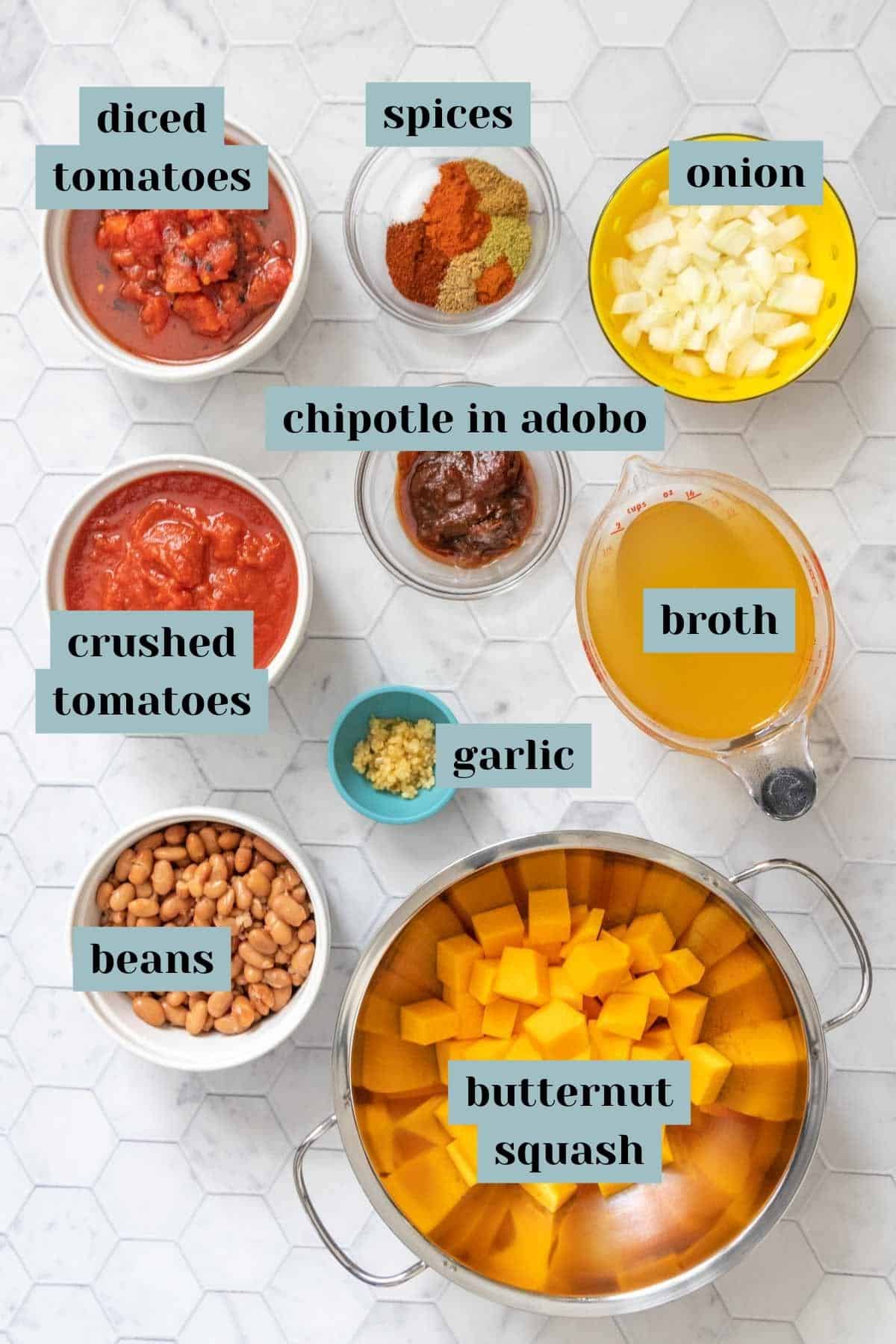 Butternut squash chili ingredients on a tile surface with labels.