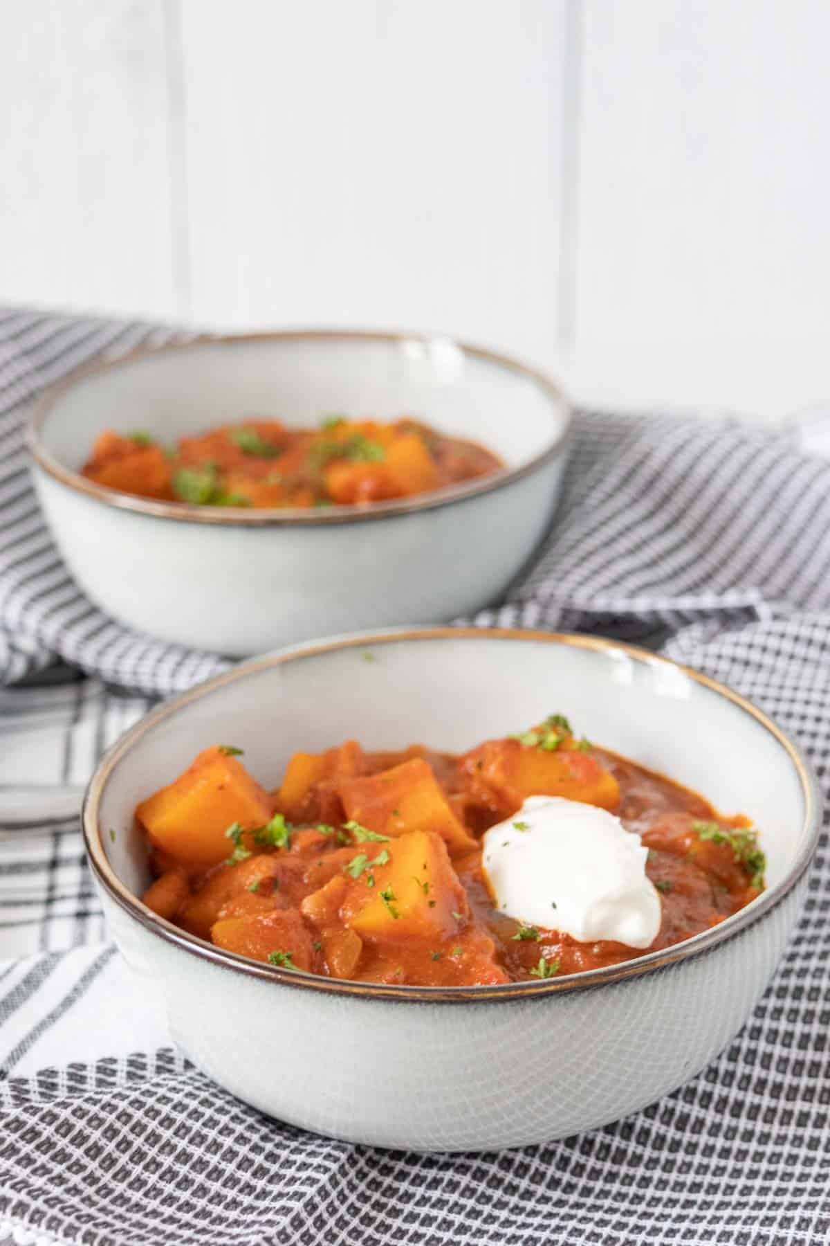 Bowls of butternut squash chili on black and white napkins.