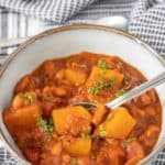 Gray bowl of butternut squash chili with a spoon.