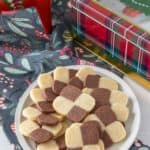 Plate full of checkerboard cookies with a holiday napkin and decor.