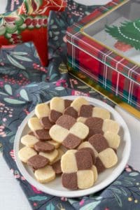 Plate full of checkerboard cookies with a holiday napkin and decor.