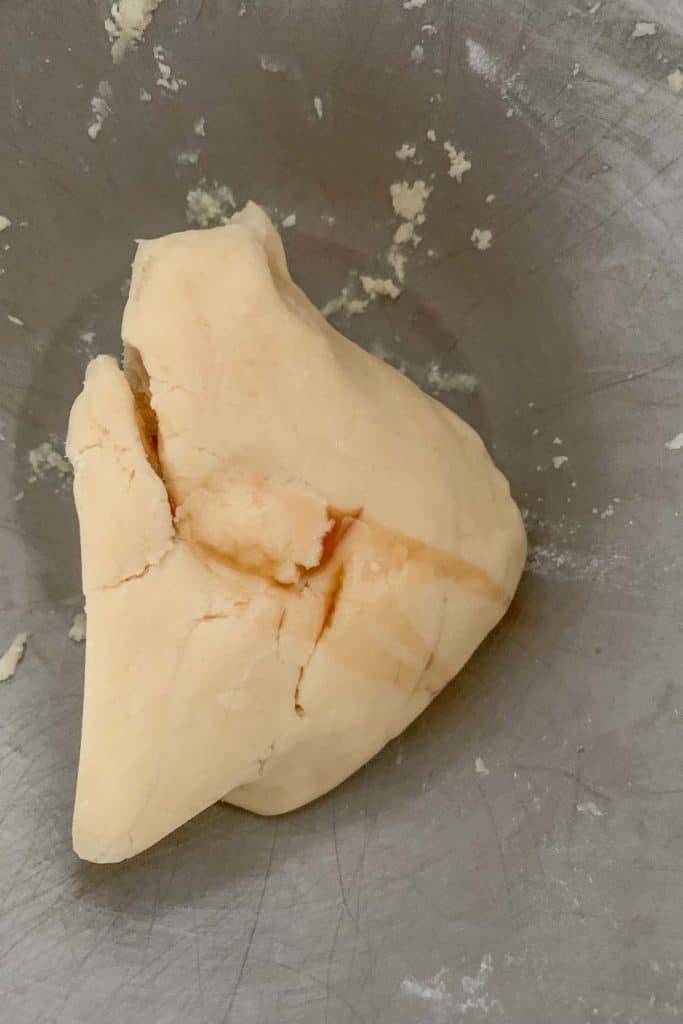 Adding vanilla to checkerboard cookie dough in a bowl.