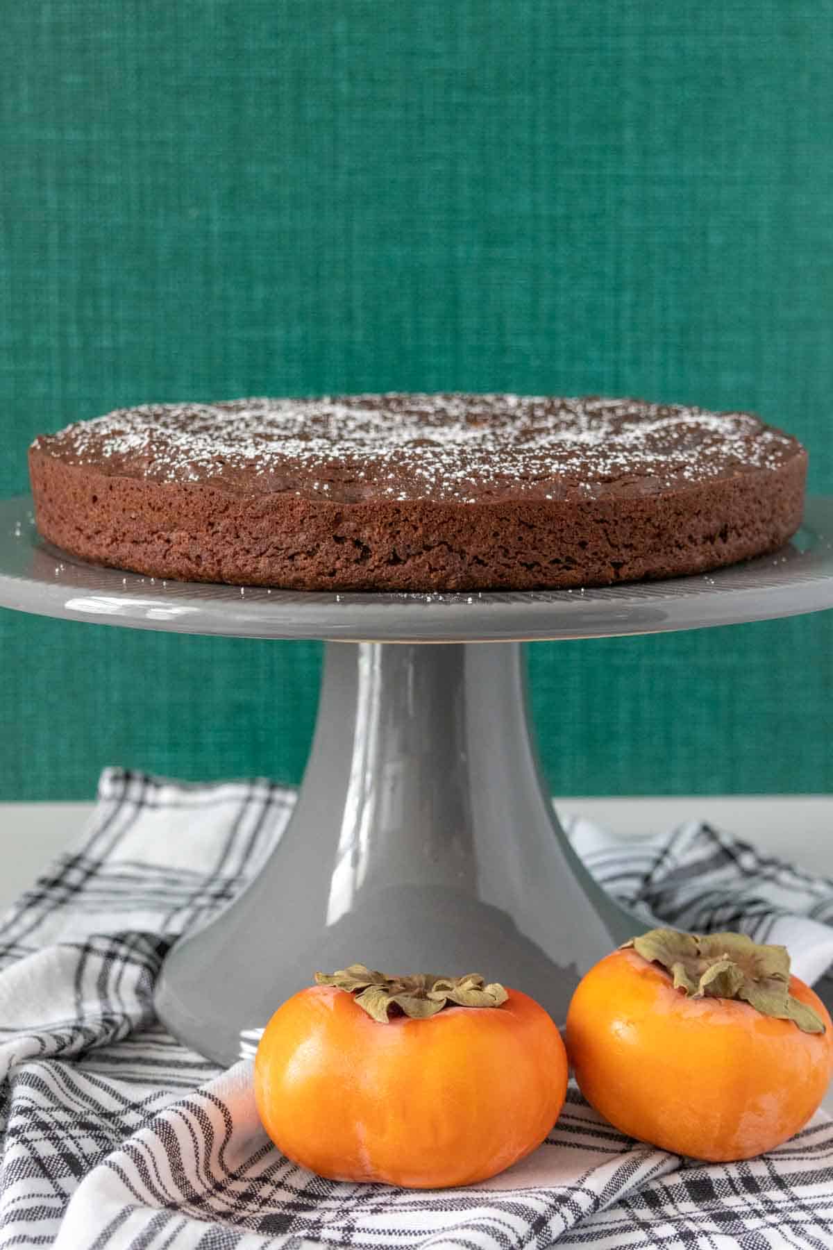 Chocolate persimmon cake on a gray cake stand.