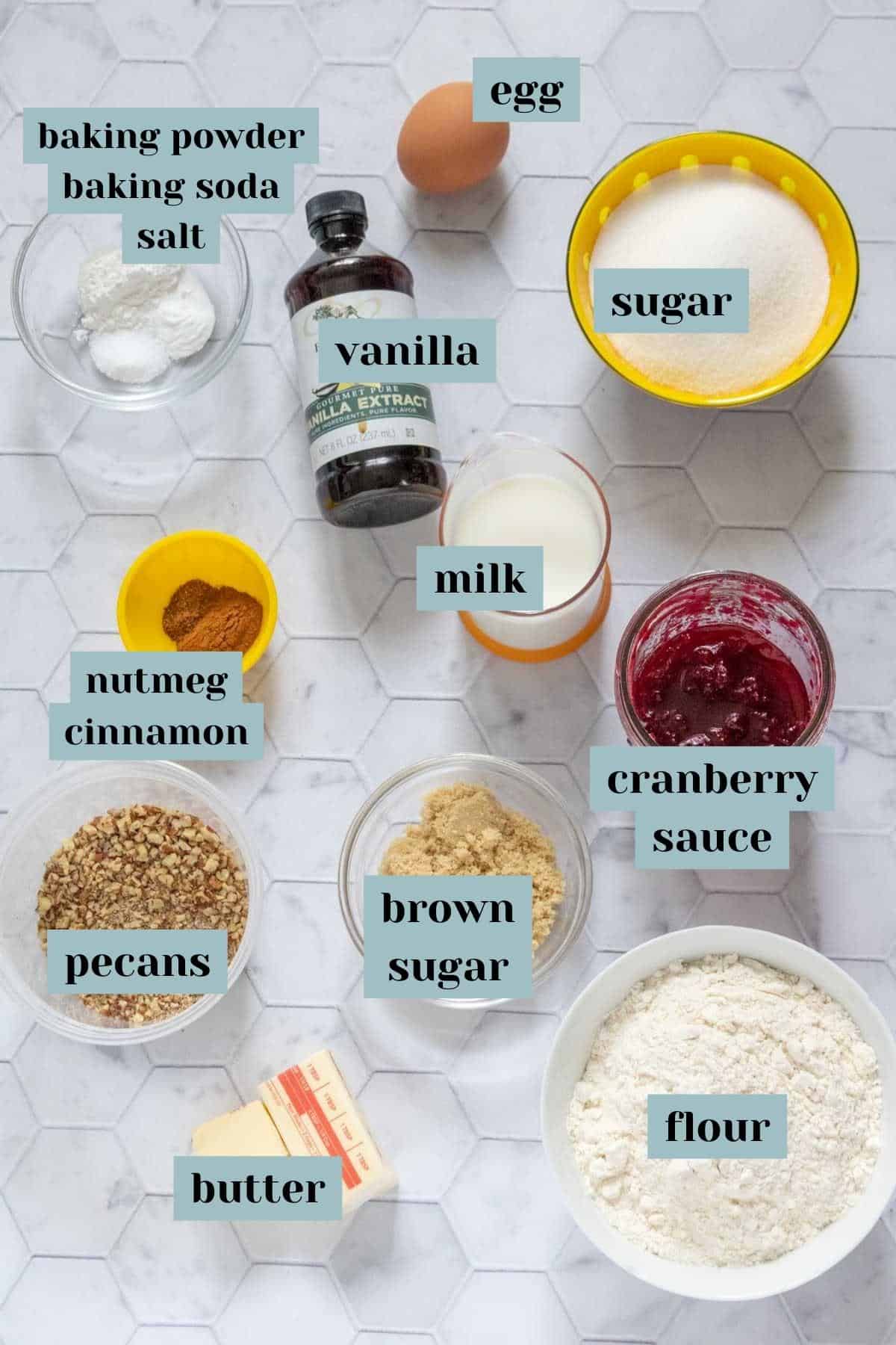 Ingredients for cranberry coffee cake on a tile surface with labels.