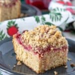 Close up of a slice of cranberry coffee cake with pecan streusel.