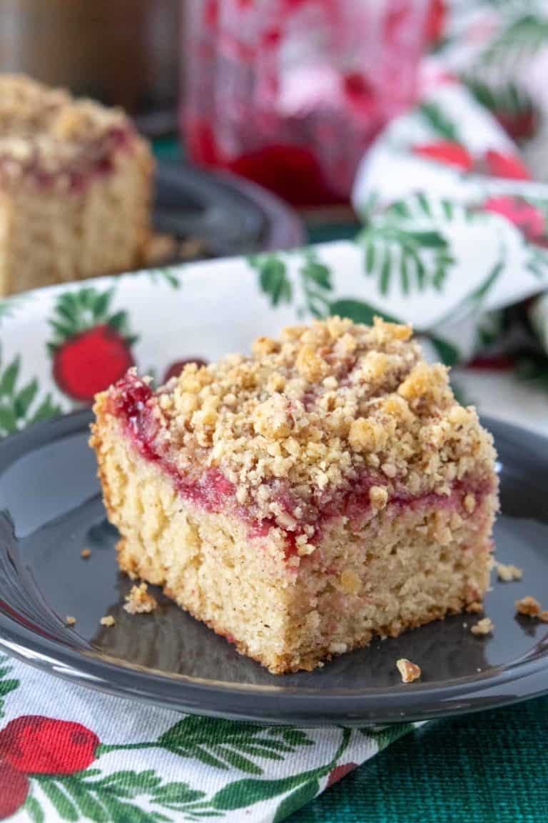 Close up of a slice of cranberry coffee cake with pecan streusel.