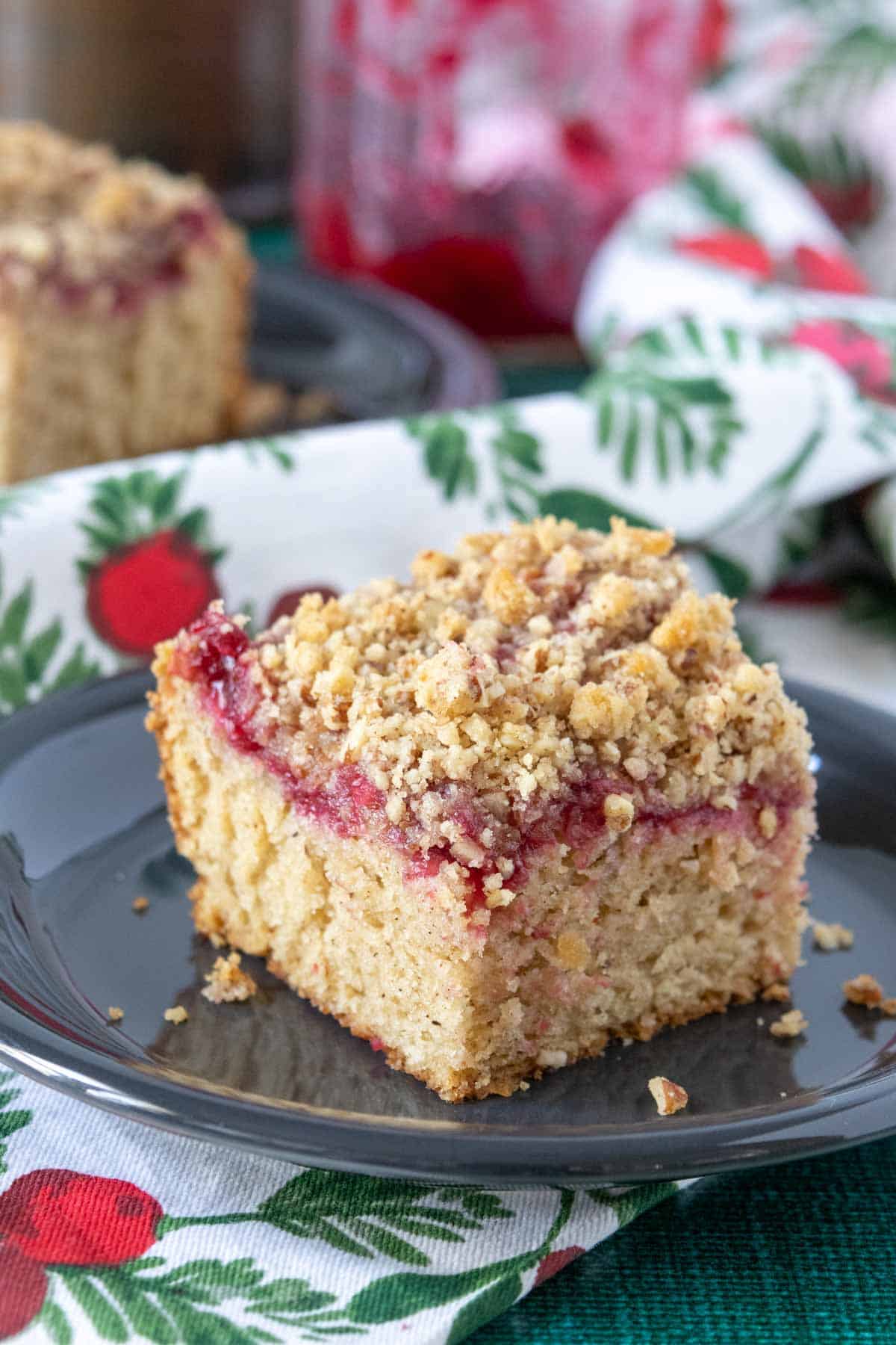 Close up of a slice of cranberry coffee cake with pecan streusel.