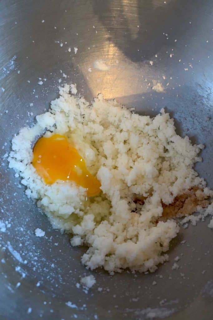 Adding egg and vanilla to butter and sugar mixture.