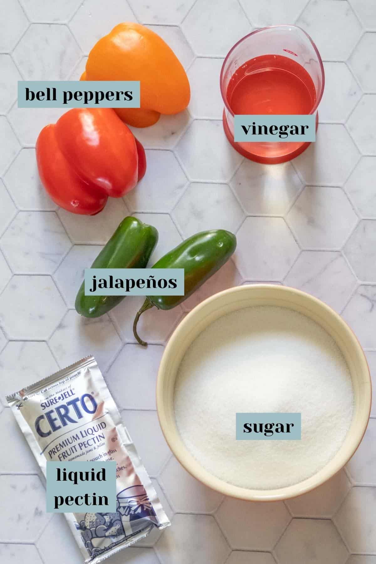 Ingredients for jalapeño jelly on a tile surface with labels.