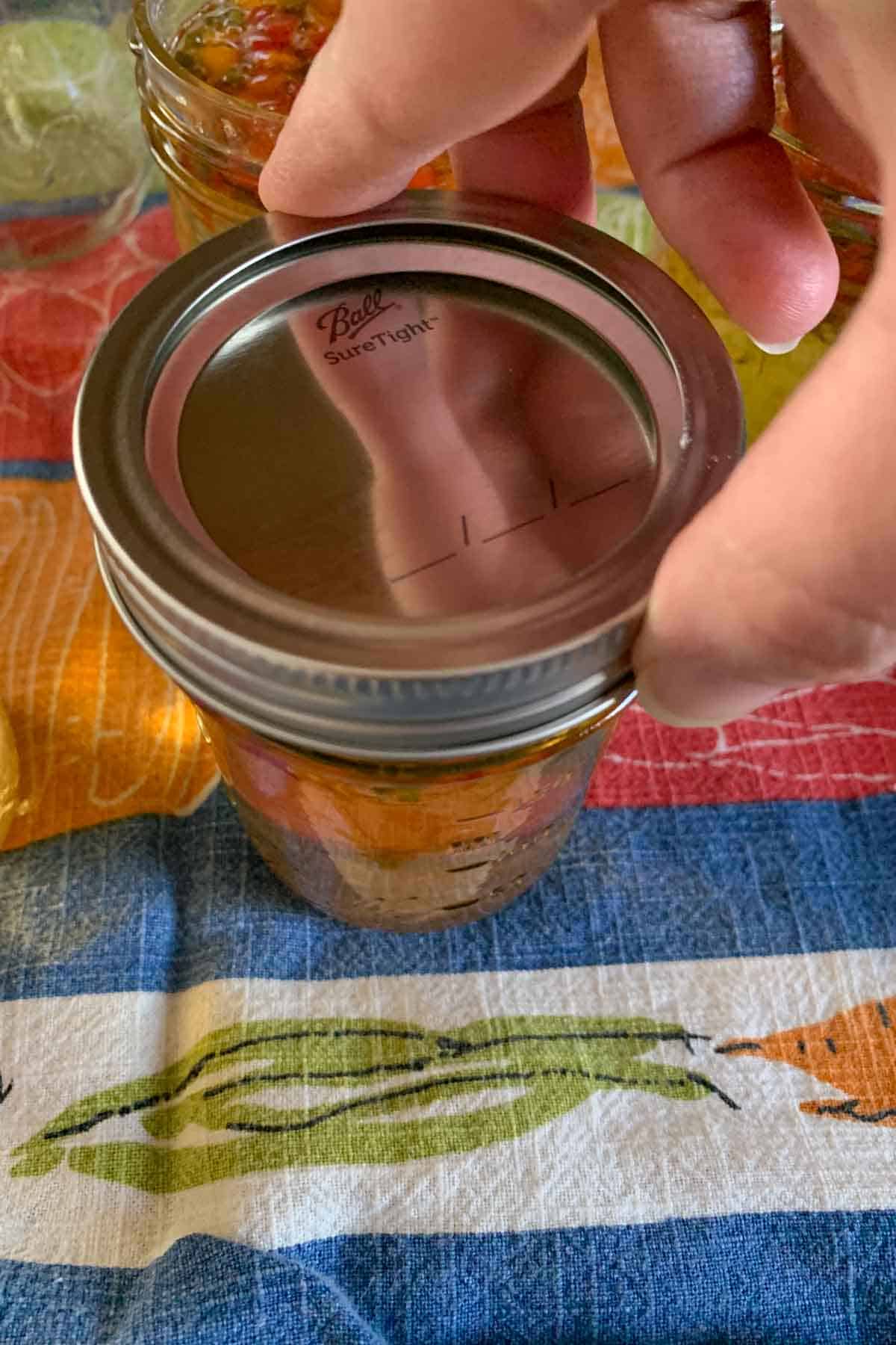 Adding lids and rings to jars of jalapeño jelly.