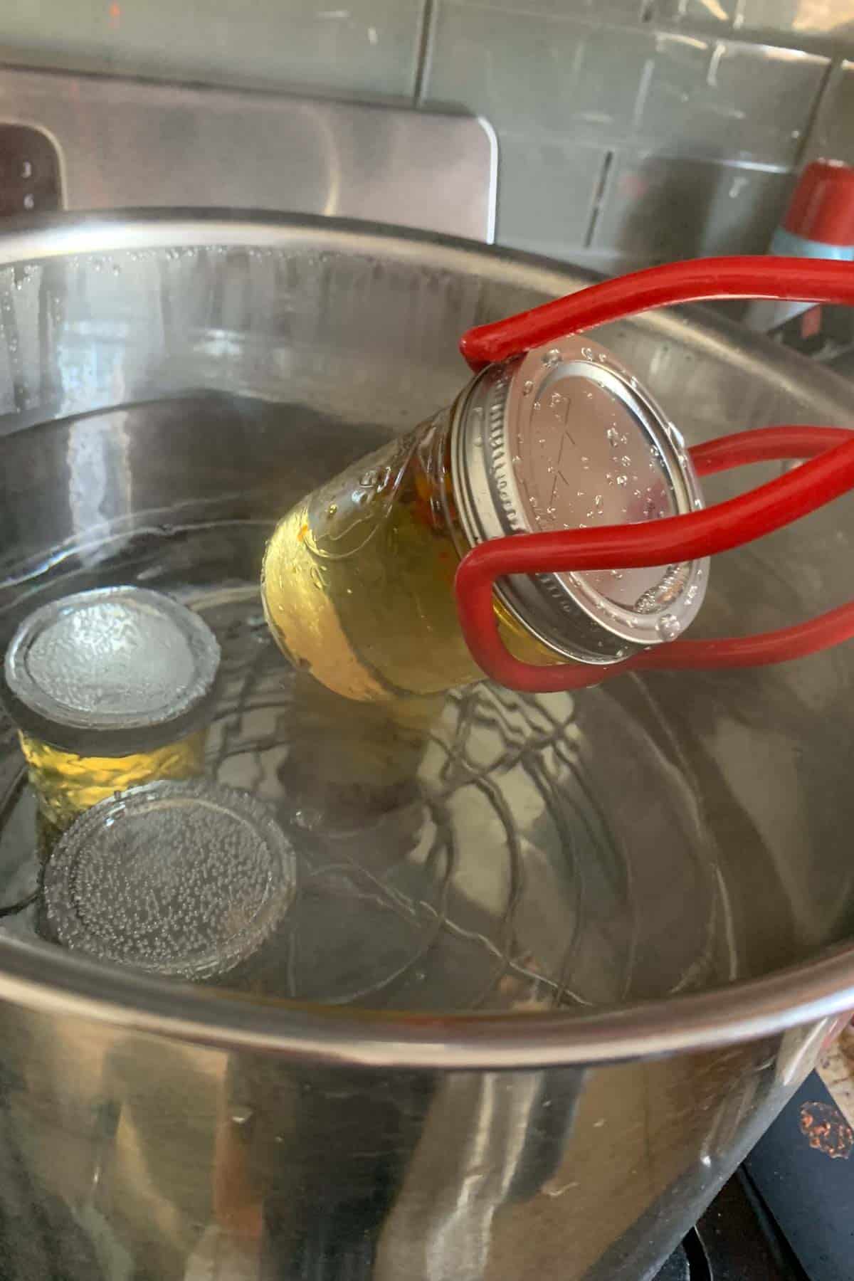 Removing pepper jelly from a water bath canner using a jar lifter.