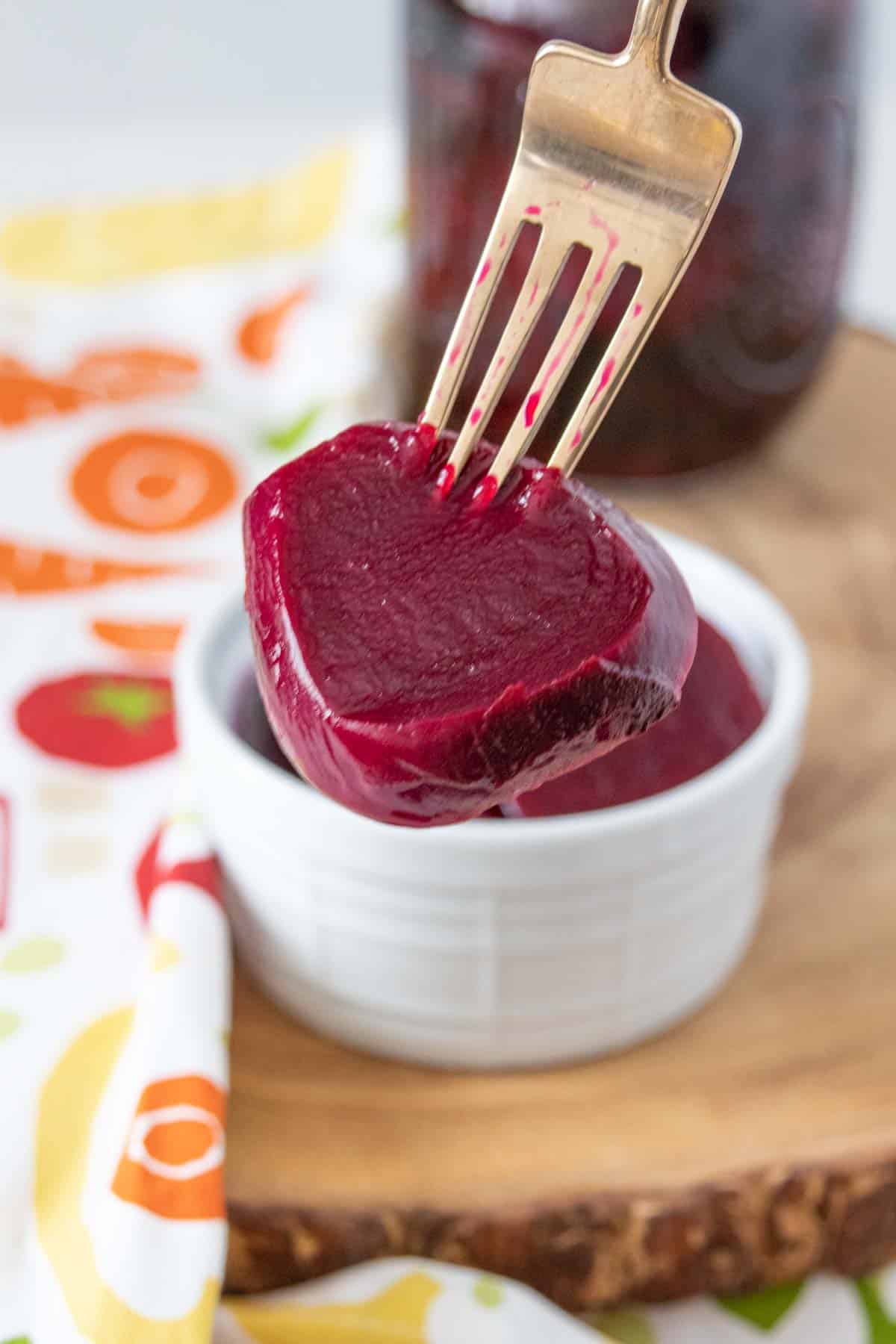 Fork holding up a slice of pickled beet.