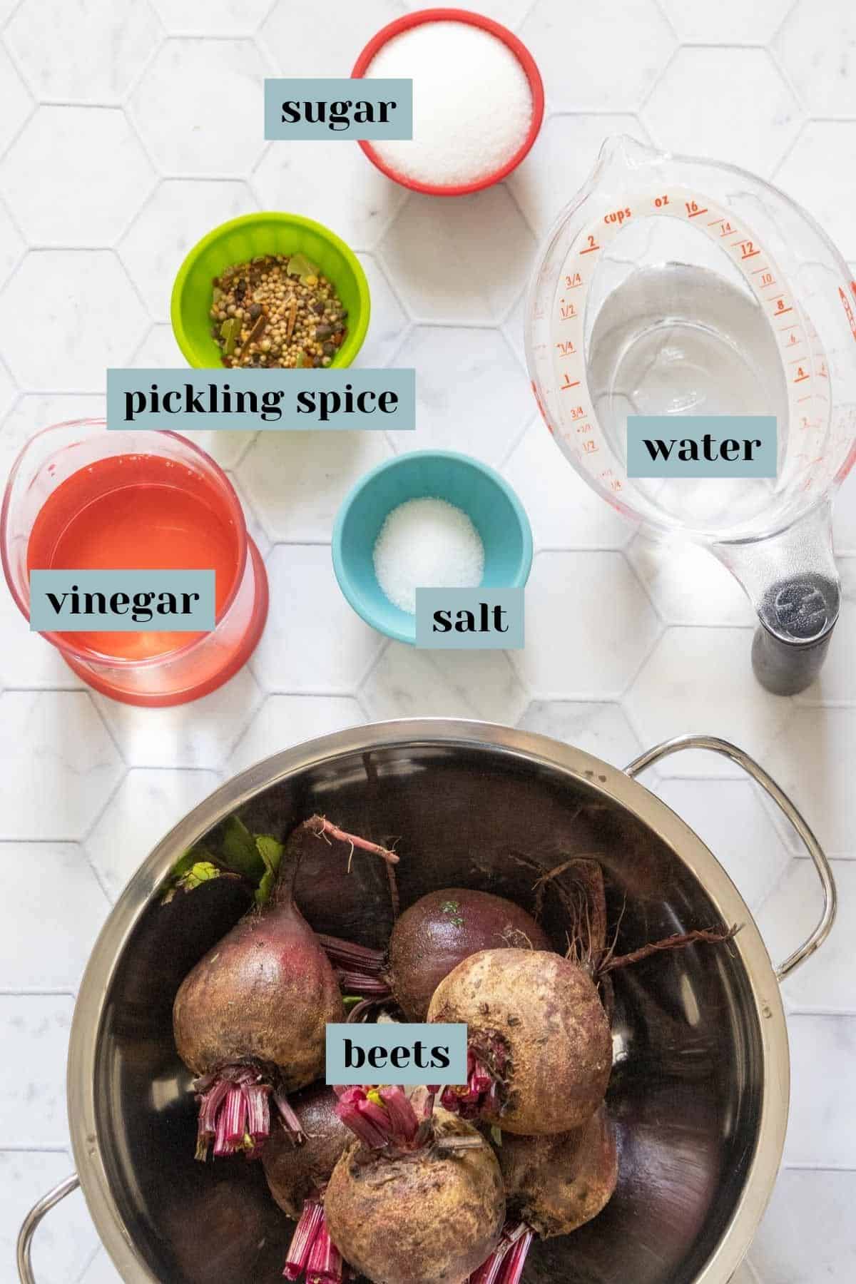 Ingredients for pickled beets on a tiled surface with labels.