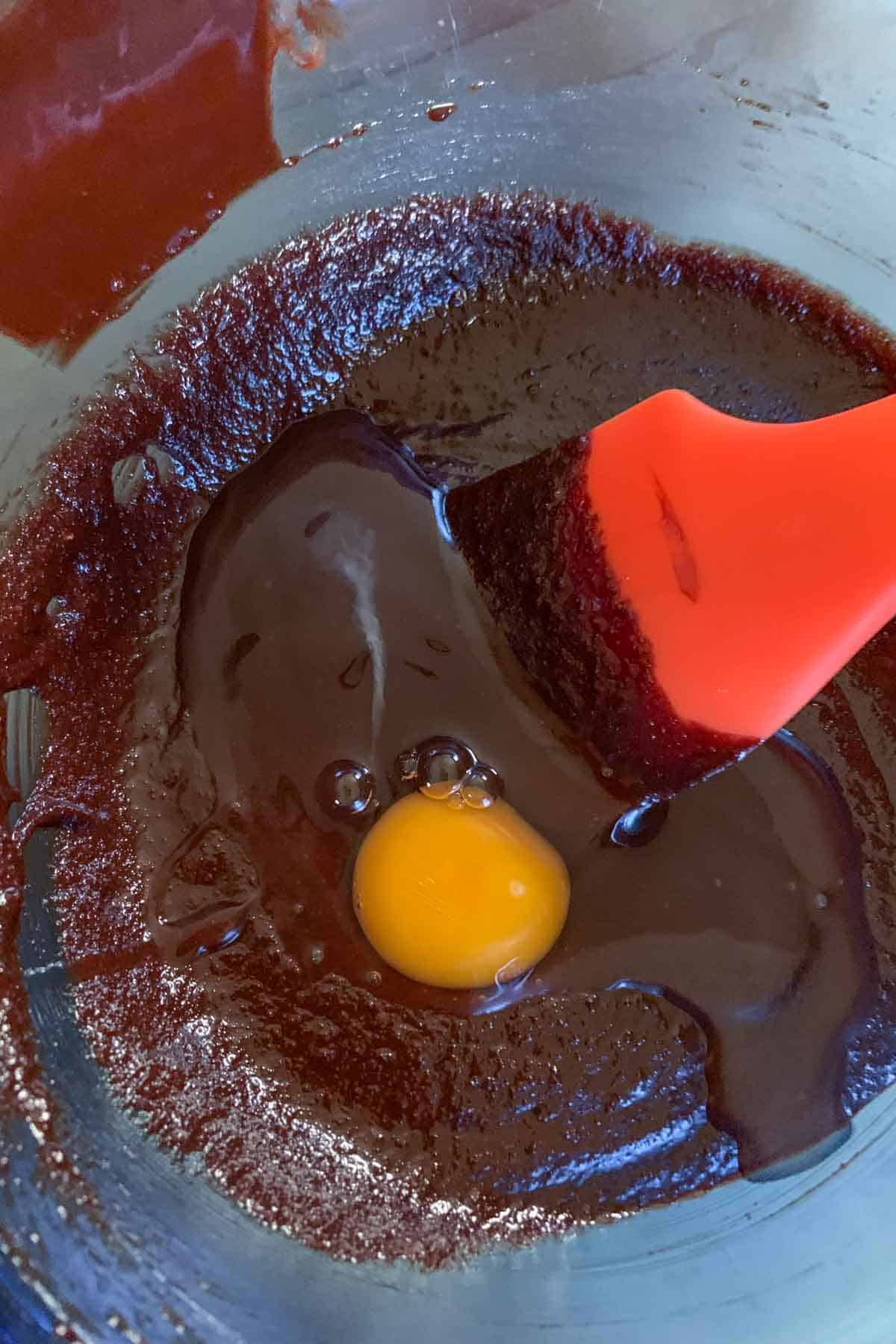 Adding egg to chocolate mixture for brownies.