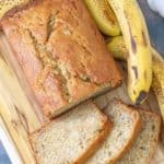 Loaf of banana bread with slices cut on a cutting board.