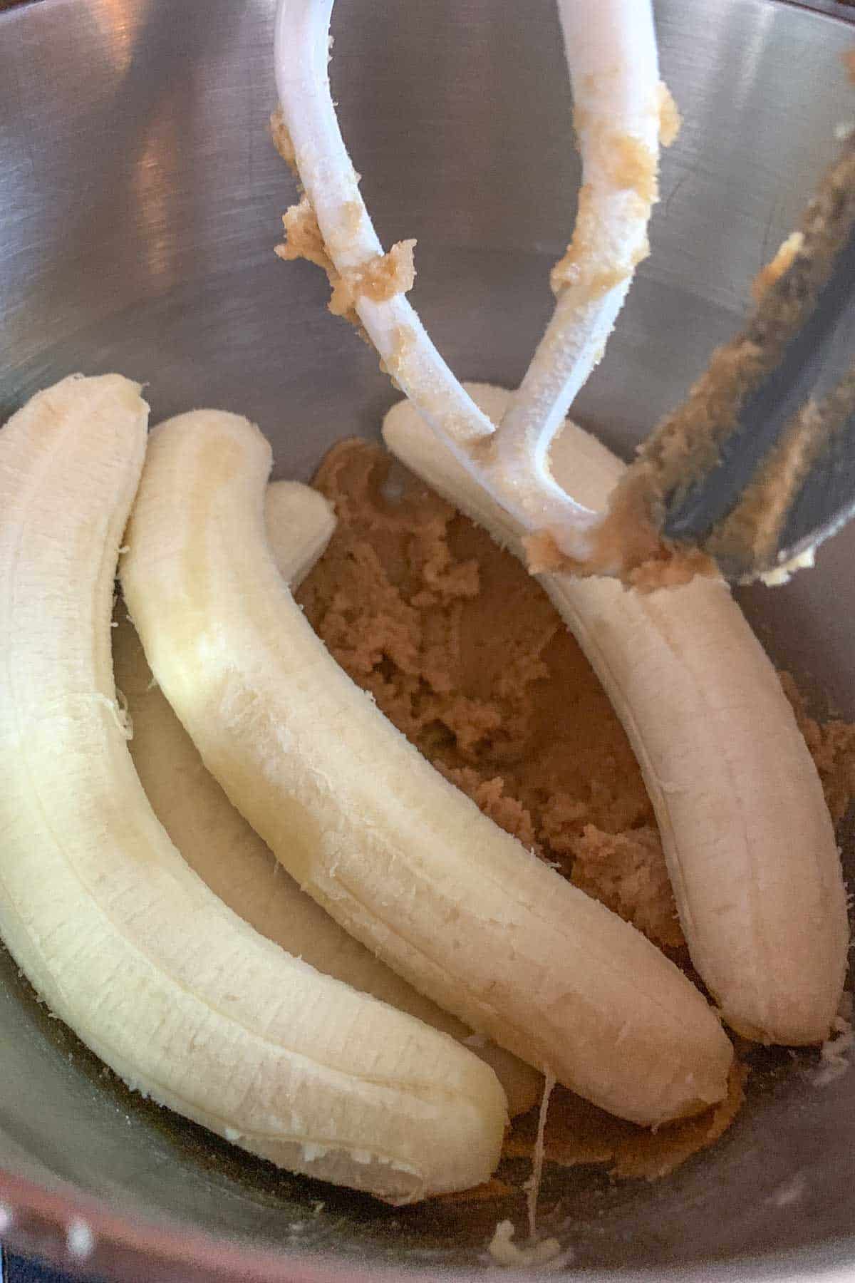 Peeled bananas added to bowl of creamed butter and sugar.