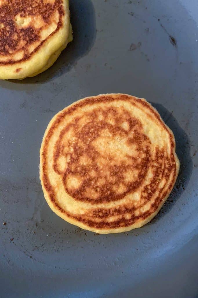 Cooking cornmeal pancakes in saute pan.