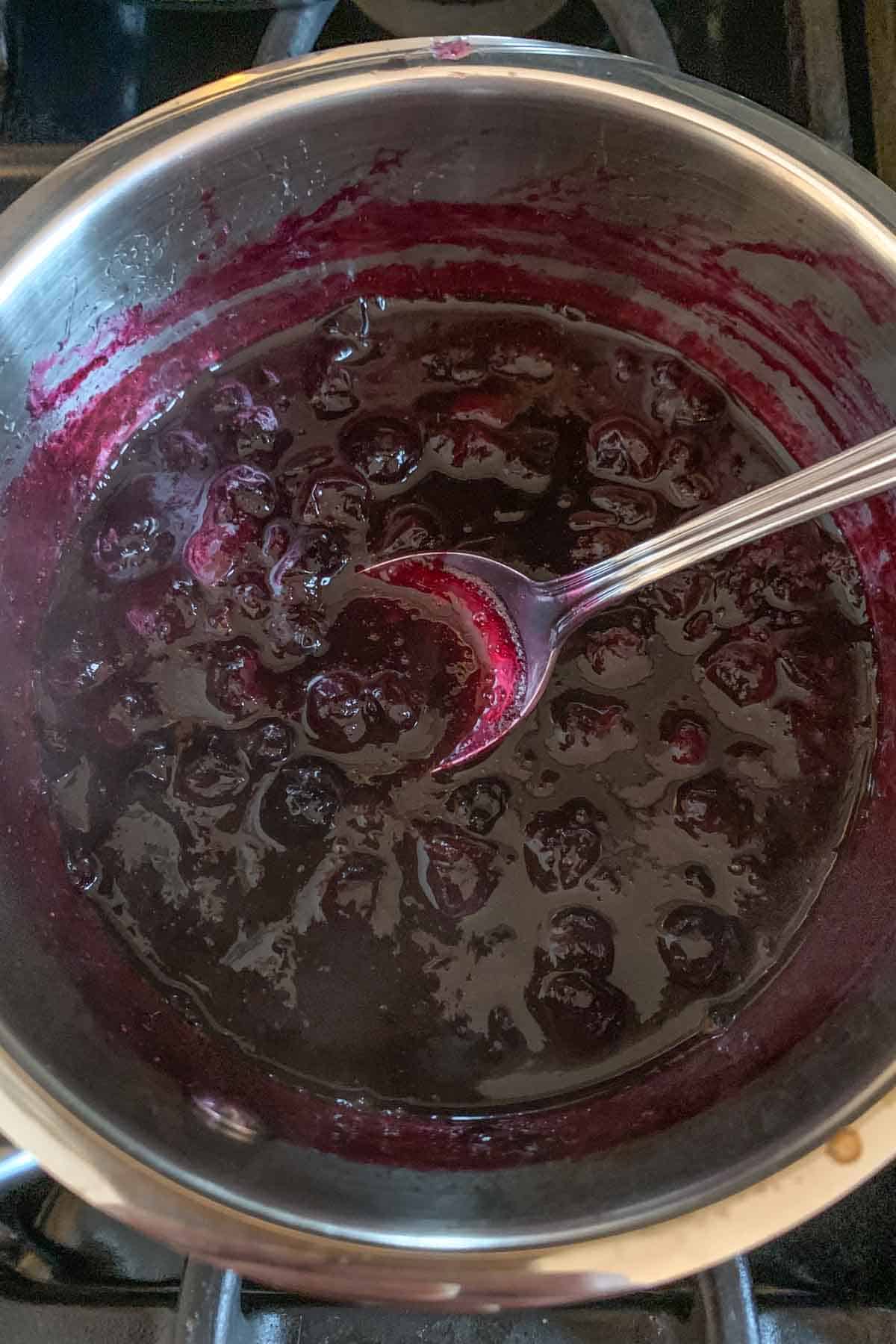 Blueberry sauce in a small saucepan on the stove.