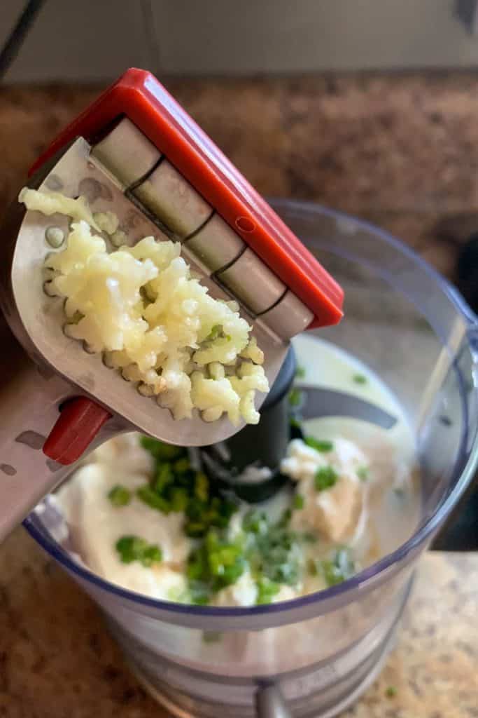 Garlic being pushed through a garlic press.