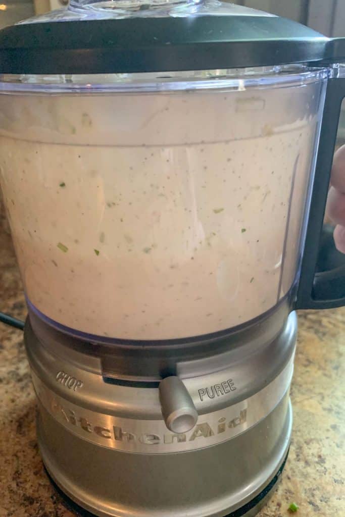 Garlic dressing being blended in a food processor.