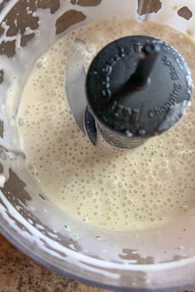 Food processor filled with blended garlic dressing.