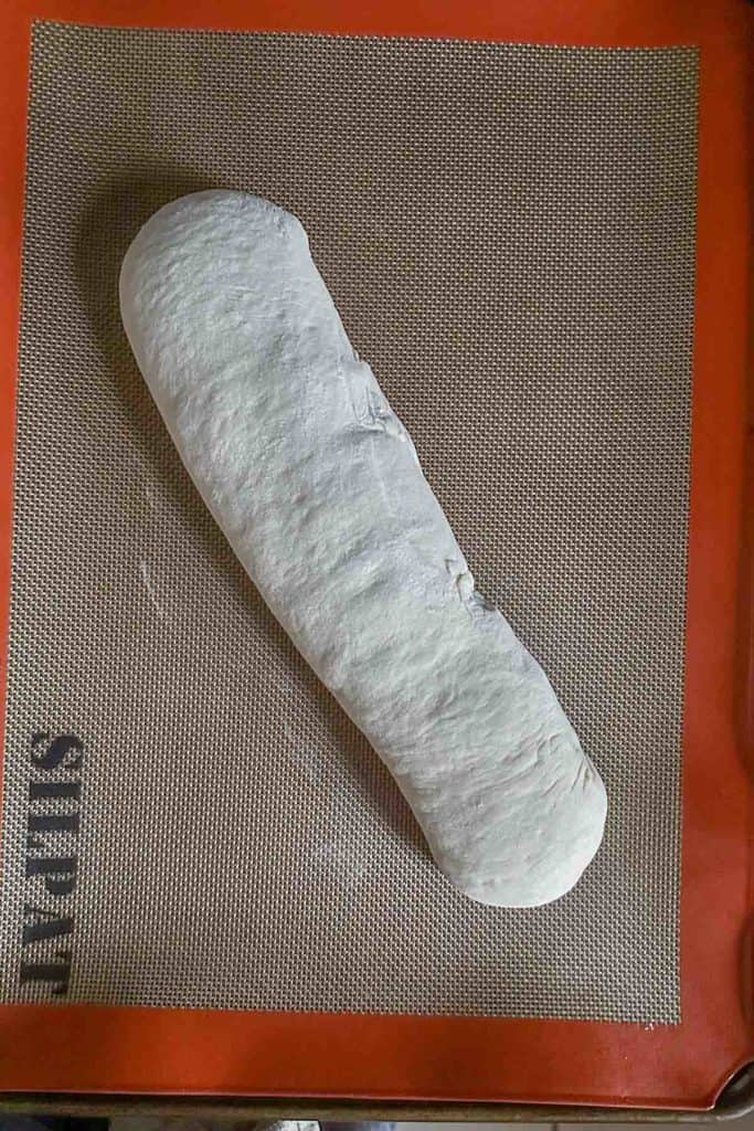 Loaf of unbaked French bread on a silpat lined baking sheet.