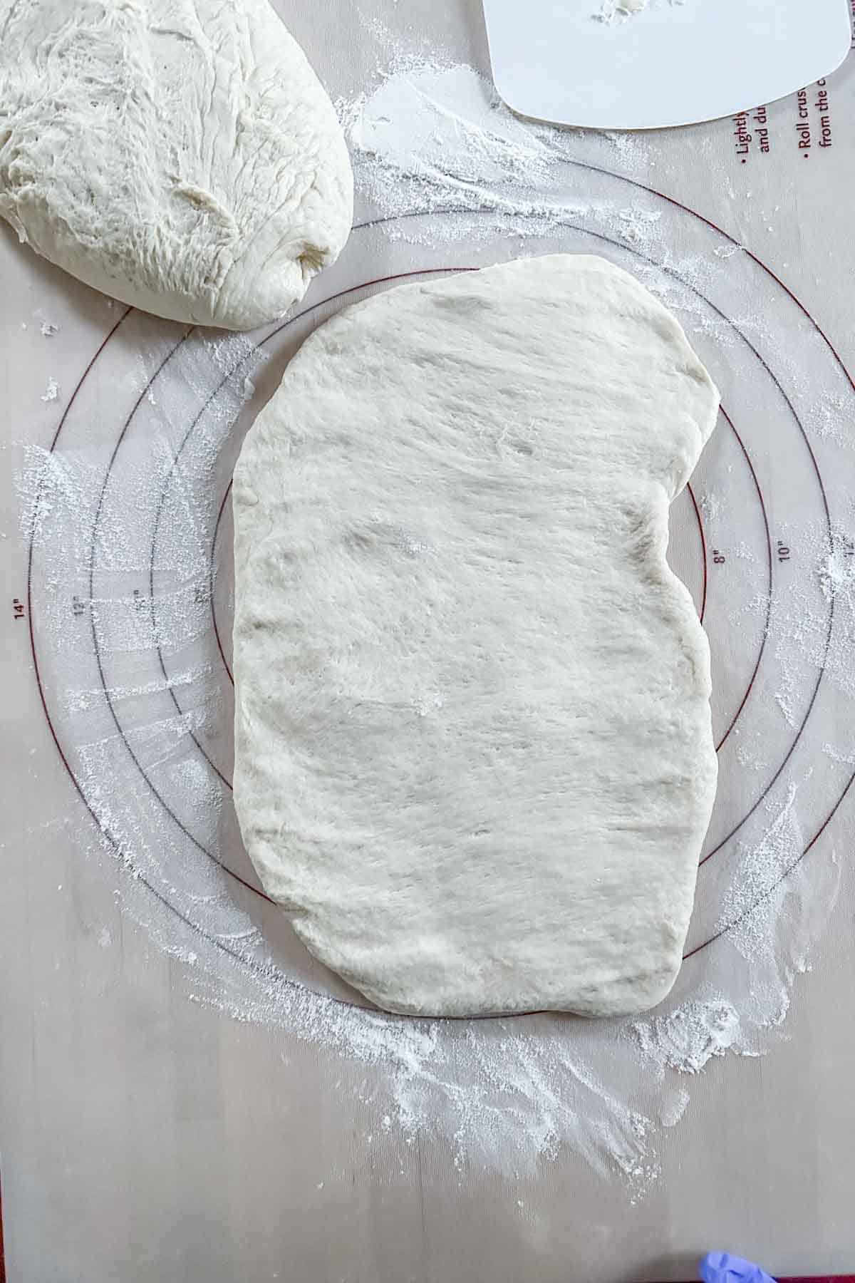 Bread dough patted into a rectangle before shaping.