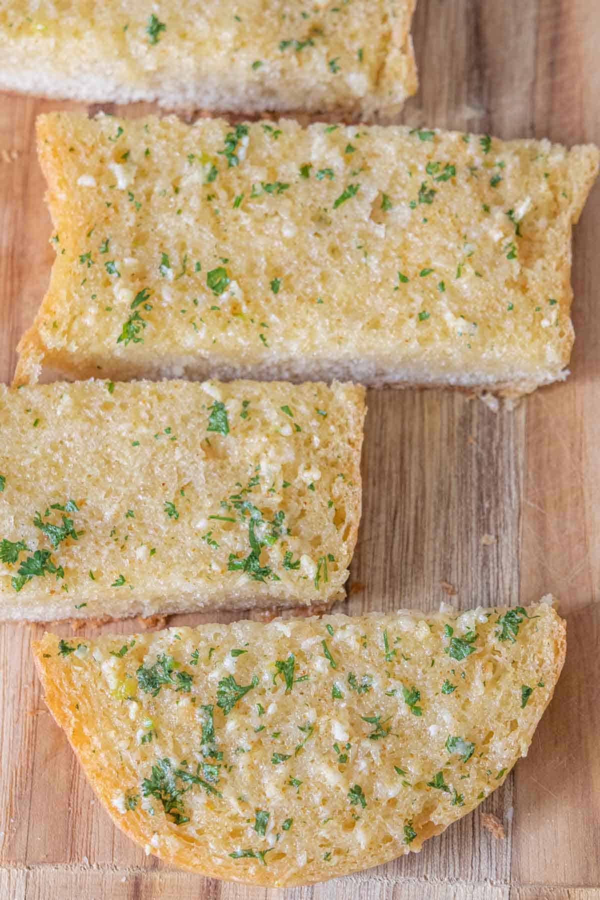 Pieces of homemade garlic bread on a cutting board.