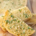 Sliced garlic bread close up on a wooden cutting board.