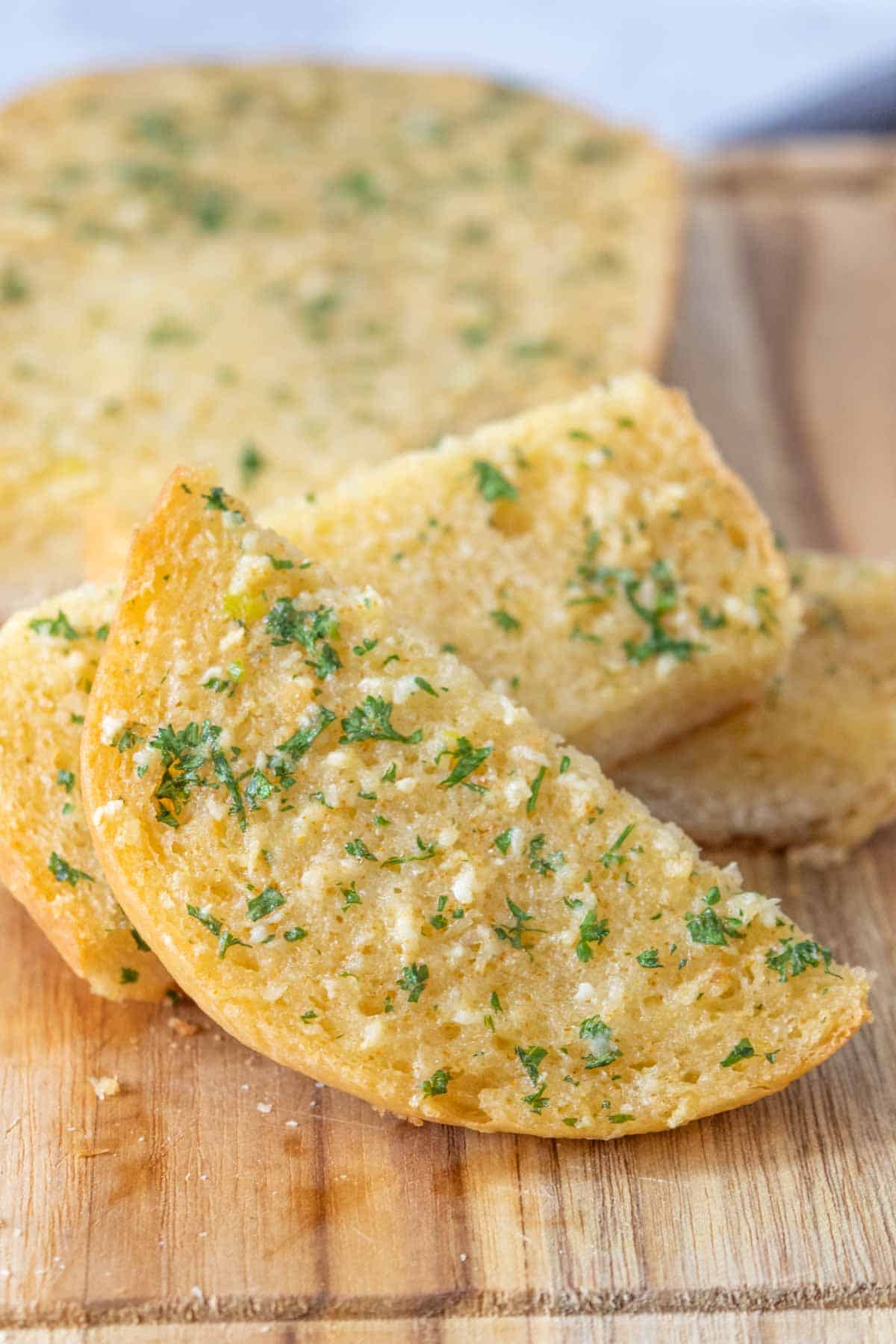 Sliced garlic bread close up on a wooden cutting board.