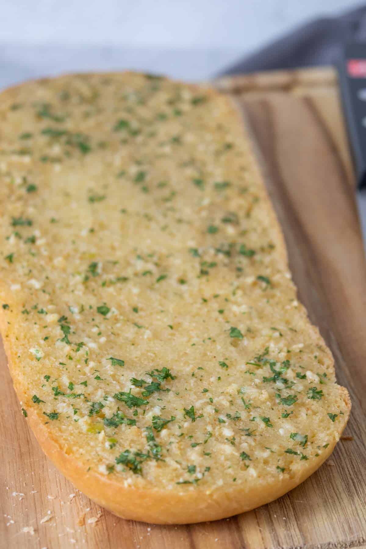 Half a loaf of homemade garlic bread on a cutting board.