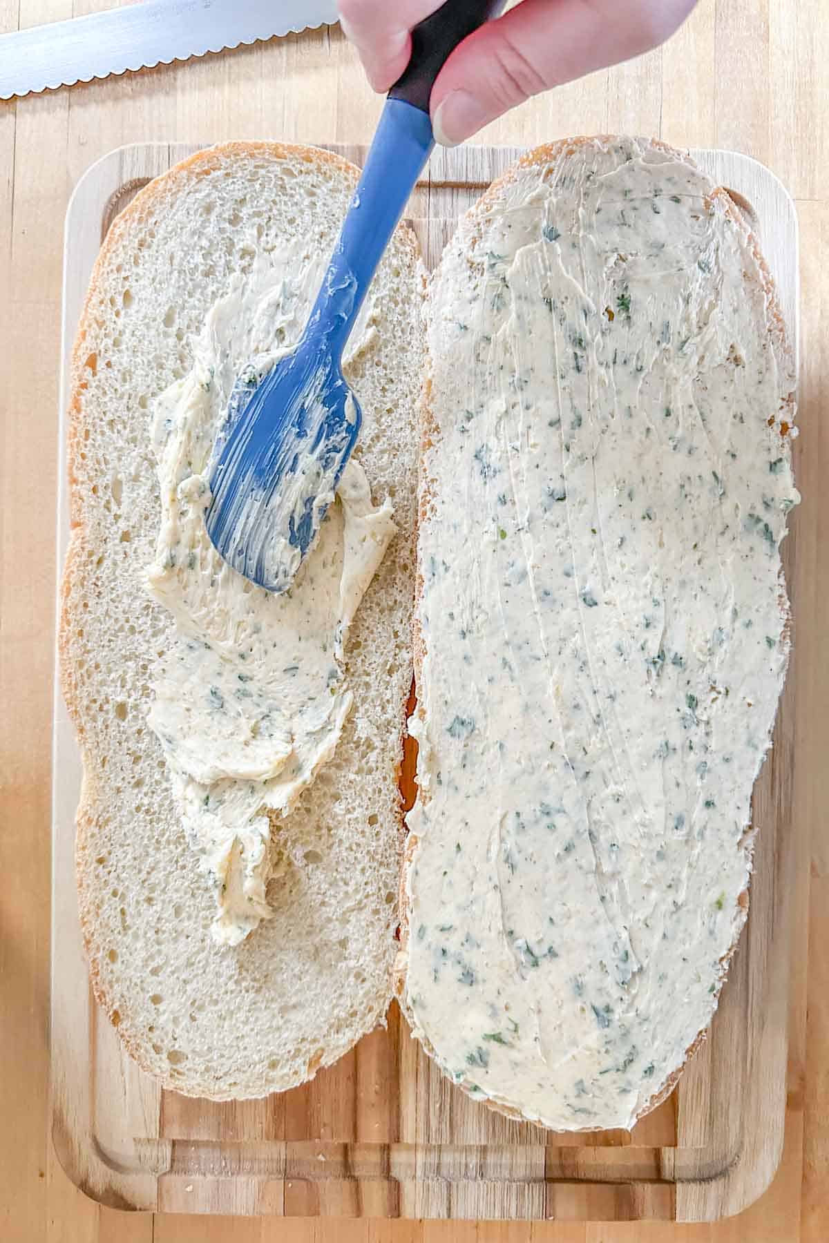 Spreading garlic butter onto bread to make homemade garlic bread.