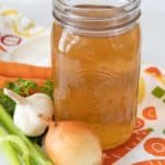 Jar of vegetable broth on a vegetable-printed towel.