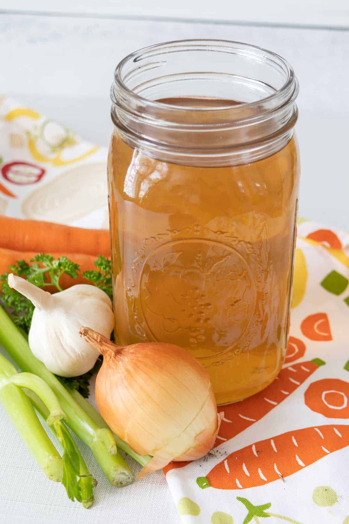 Jar of vegetable broth on a vegetable-printed towel.