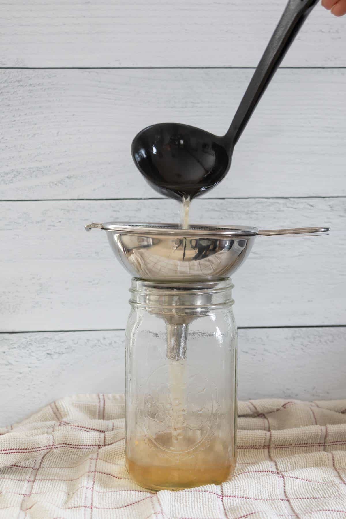 Pouring stock into jar with a ladle.